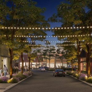 Outside shopping center at nighttime with strung up lighting and people walking.