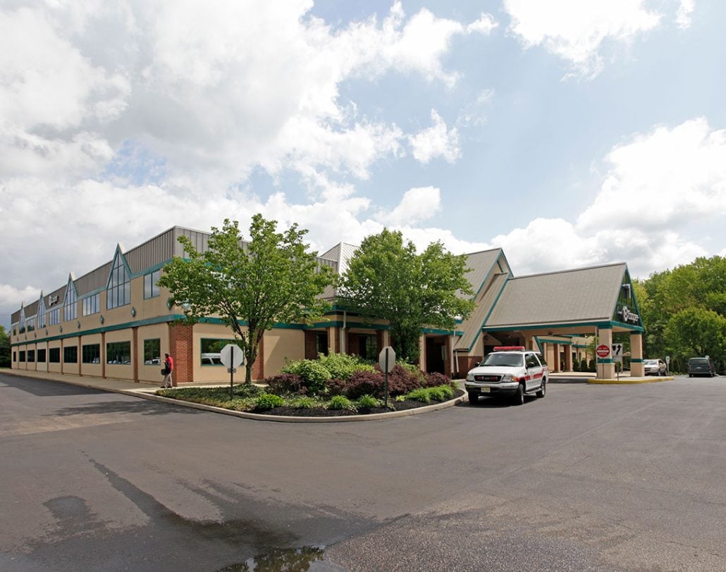 The exterior view from the parking lot of the Voorhees building with a medical vehicle parked in front of the entrance.